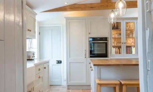 Modern kitchen with wooden countertops, glass pendant lights, an oven, and white cabinets.
