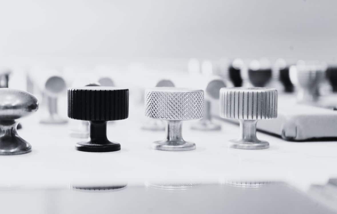 Close-up of various metallic and black knobs on a white surface.
