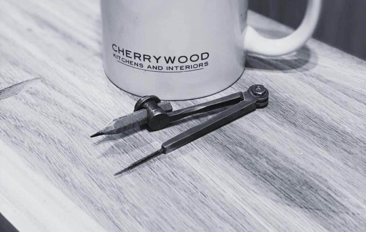 A mug and a compass on a wooden table.