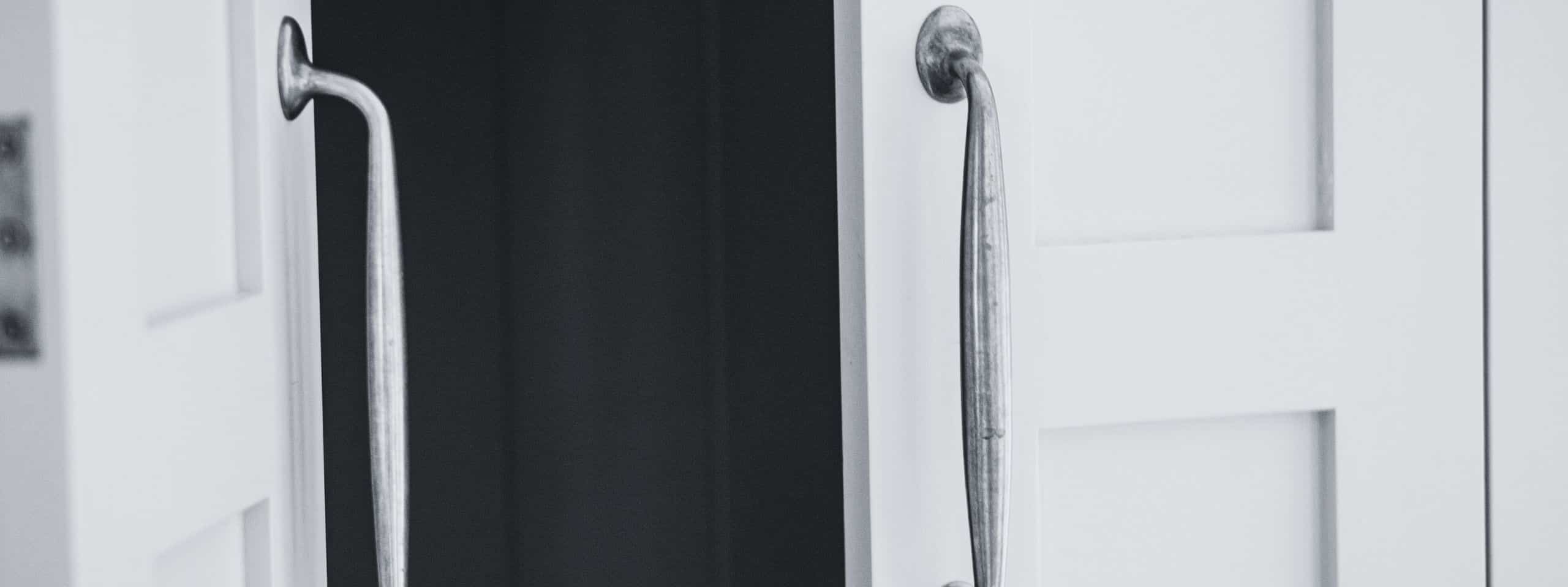 White doors with antique metal handles slightly ajar.