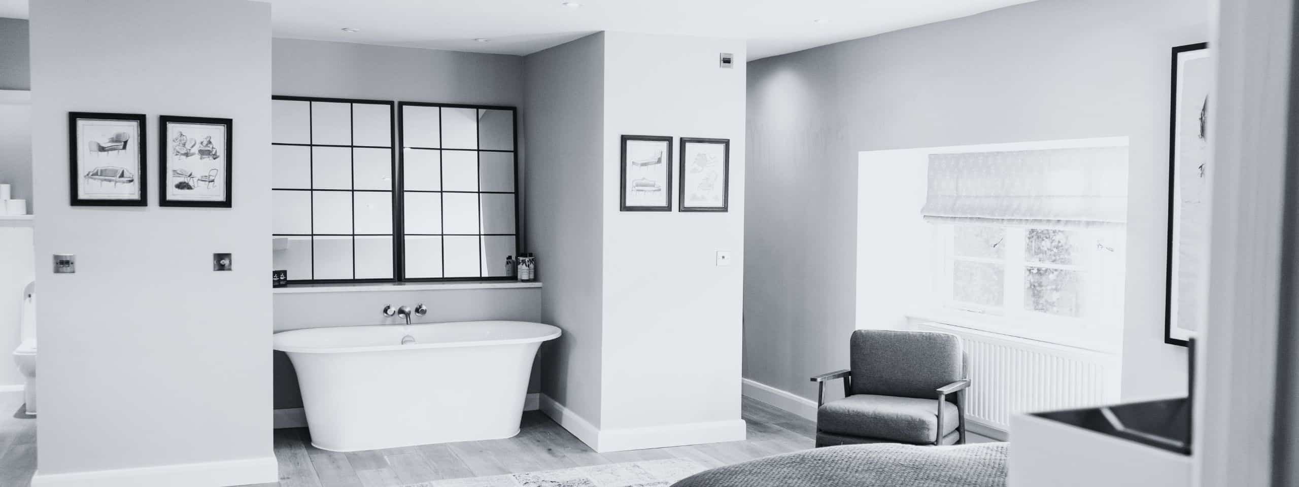 Modern bathroom with freestanding tub, framed art, and large window. Monochrome style.