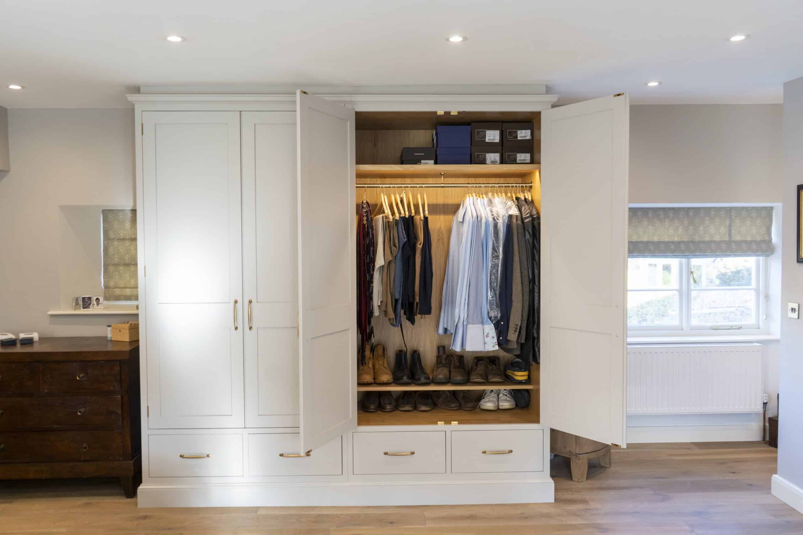 Open wardrobe with clothes, shoes, and boxes inside, in a well-lit room.