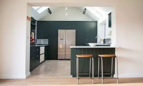 Modern kitchen with dark cabinets, stainless appliances, and a breakfast bar with two stools.