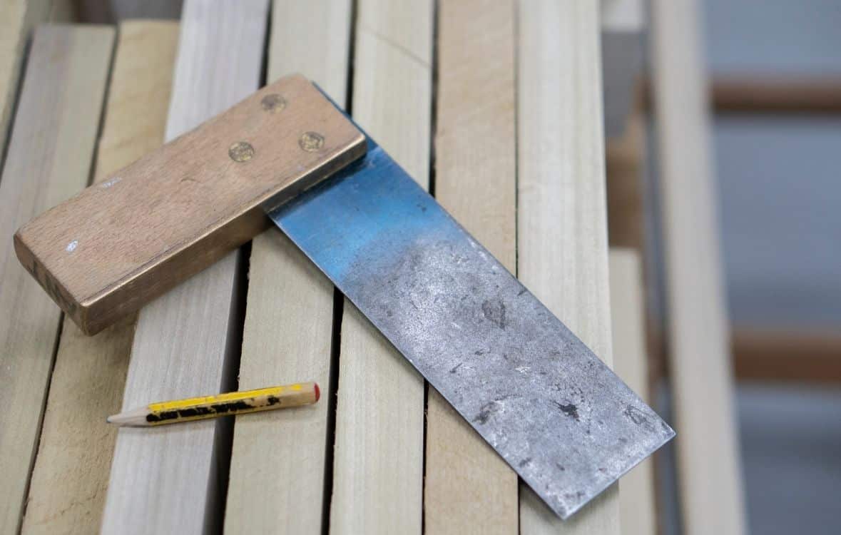 Untitled design (9) Chisel and pencil on stacked wooden planks.
