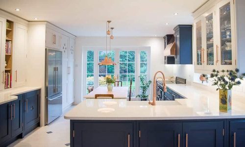 Modern kitchen with navy cabinets, white countertops, and large windows.
