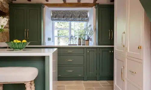 Green and white luxury kitchen with a window, island, and stool.