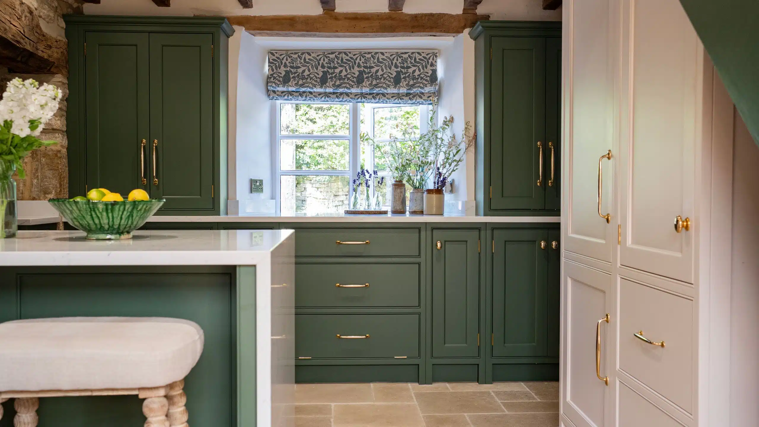 Beautiful Honest Results - Cherrywood Handmade Luxury Kitchen Spacious kitchen with white and navy cabinets, wooden floor, and bar seating under large windows.
