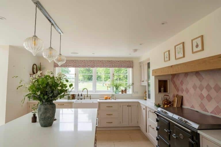 Bright kitchen with an island, wicker chairs, wood floor, and large windows letting in natural light.