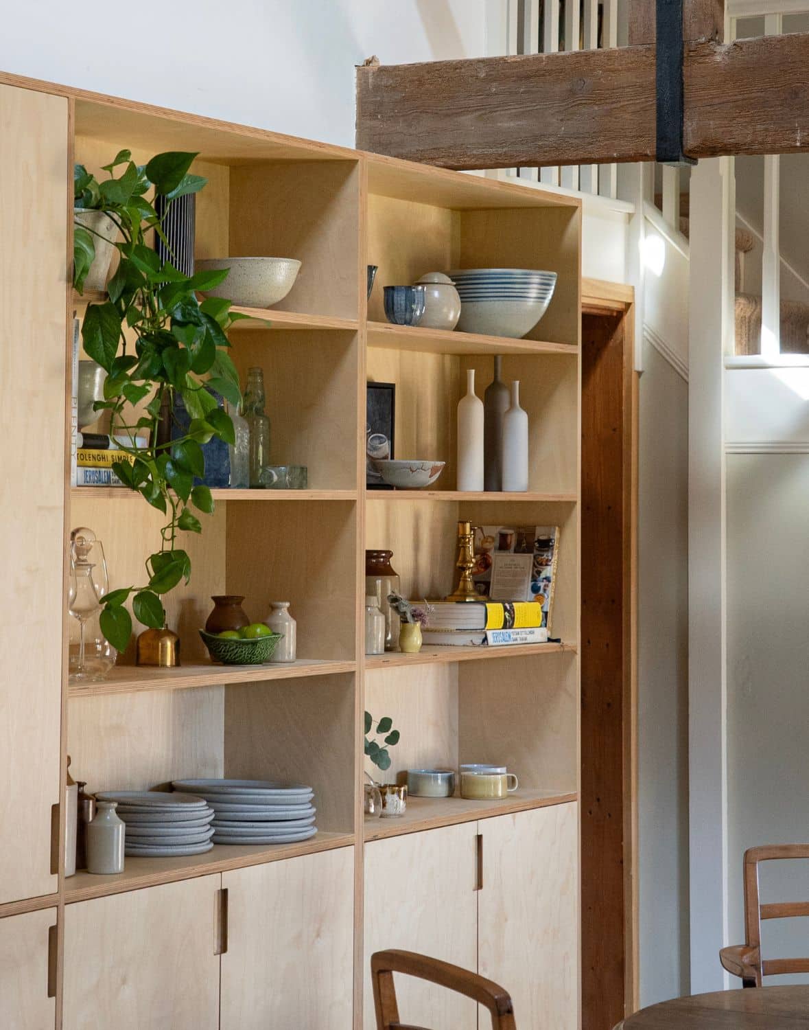 3 Cozy kitchen with wood beams, open shelving, and a window with blinds letting in sunlight.