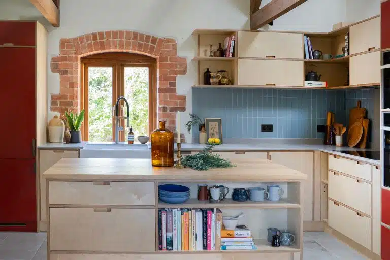Modern kitchen with dark cabinets, white countertops, and a bowl. Blue wall with framed text and a lamp in the background.