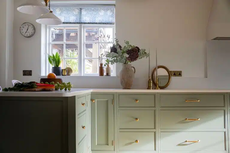 Modern kitchen with blue cabinets, white countertops, and a large window.
