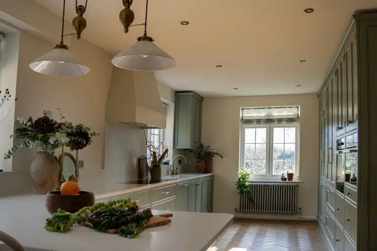 2 Spacious kitchen with white and navy cabinets, wooden floor, and bar seating under large windows.