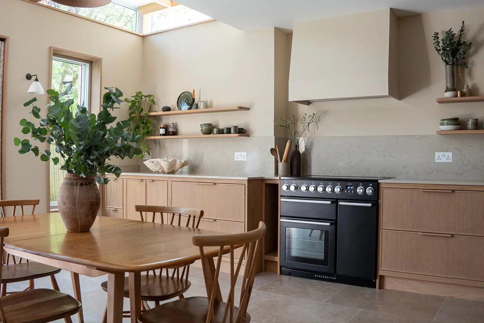 Cherrywood Bright kitchen with white cabinets, wooden stools, open shelves, and sunlight streaming through the windows.