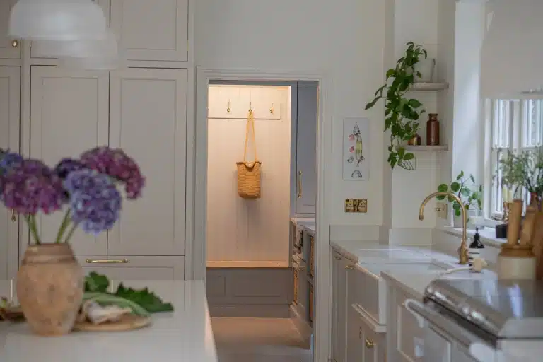 Modern kitchen with a pink island, three wooden stools, and white cabinets.