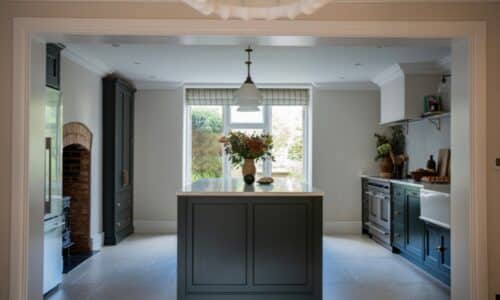 Modern kitchen with a central island, large window, and plants on the countertop.
