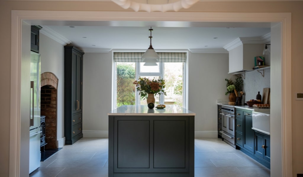 Modern kitchen with a central island, large window, and plants on the countertop.